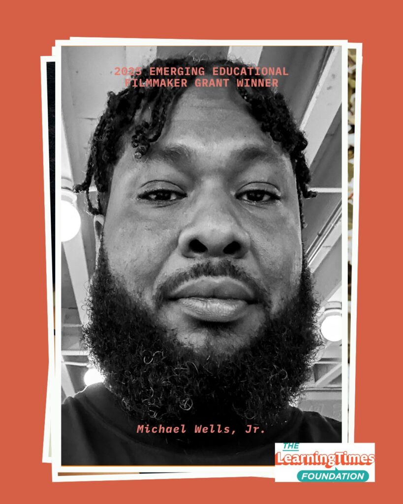 Black and white selfie portrait of Michael Wells, Jr. taken indoors. Michael hair is braided and styled with decorative beads, a full beard, and wears a black shirt. He looks directly at the camera with an indoor setting visible in the background. The image is set on an orange background with white frame borders. Text at the top reads '2025 EMERGING EDUCATIONAL FILMMAKER GRANT WINNER' in orange, with 'Michael Wells, Jr.' labeled at the bottom. The Learning Times Foundation logo appears in the bottom right corner.